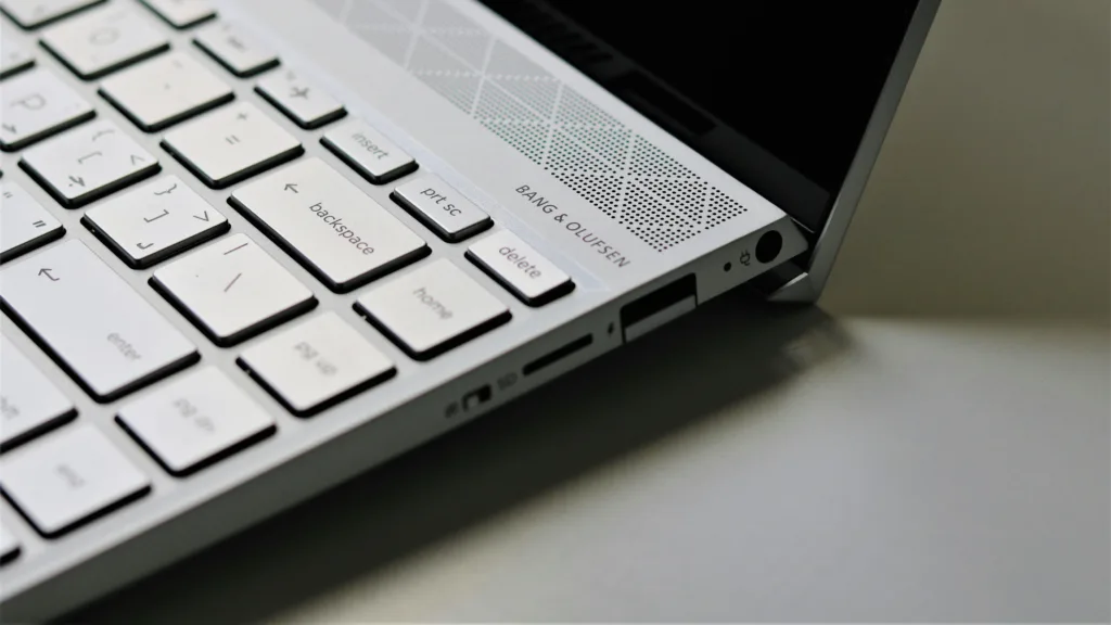 Detailed view of a silver laptop keyboard with Bang & Olufsen speaker highlighting high-quality design.